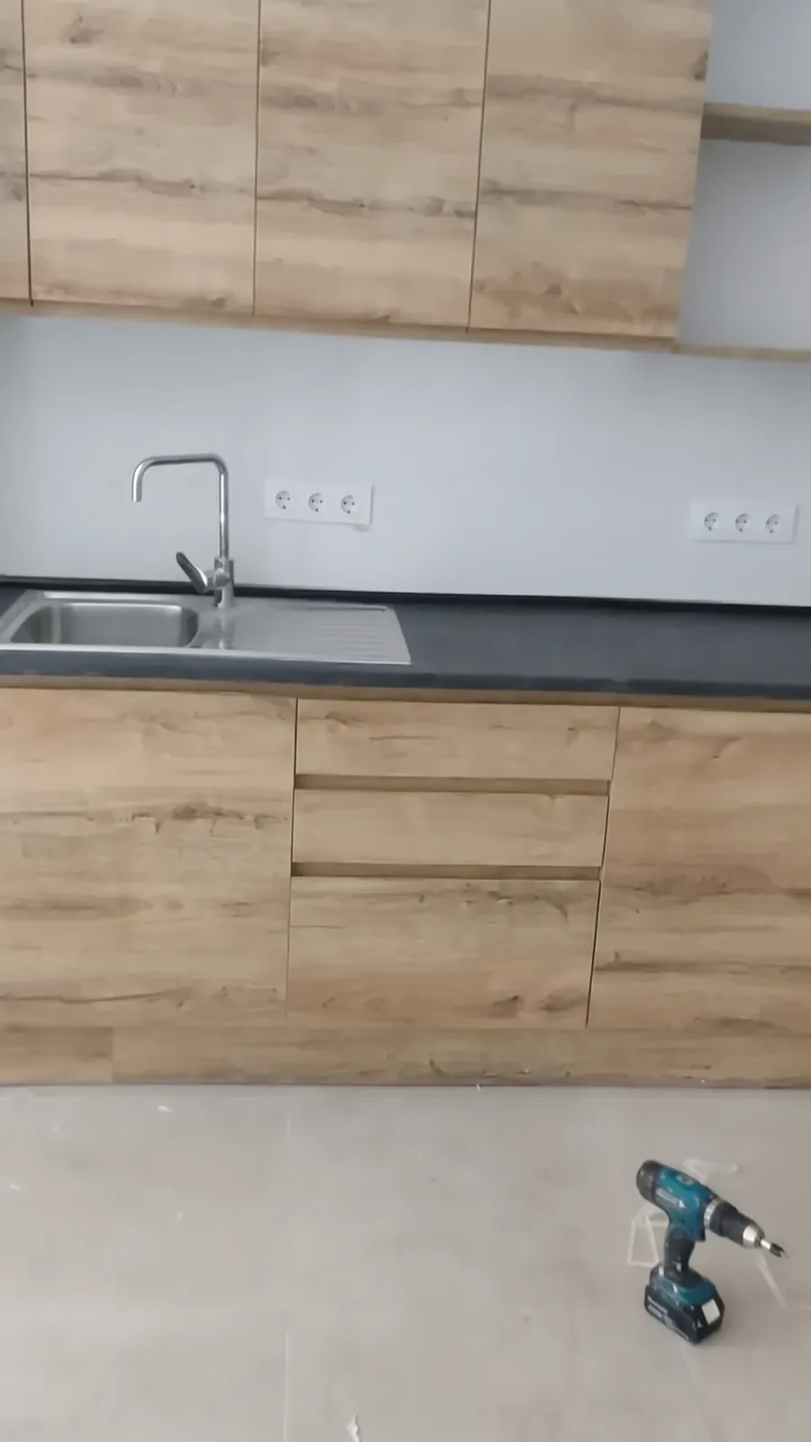 Cocina con muebles de roble, encimera negra y fregadero de acero inoxidable