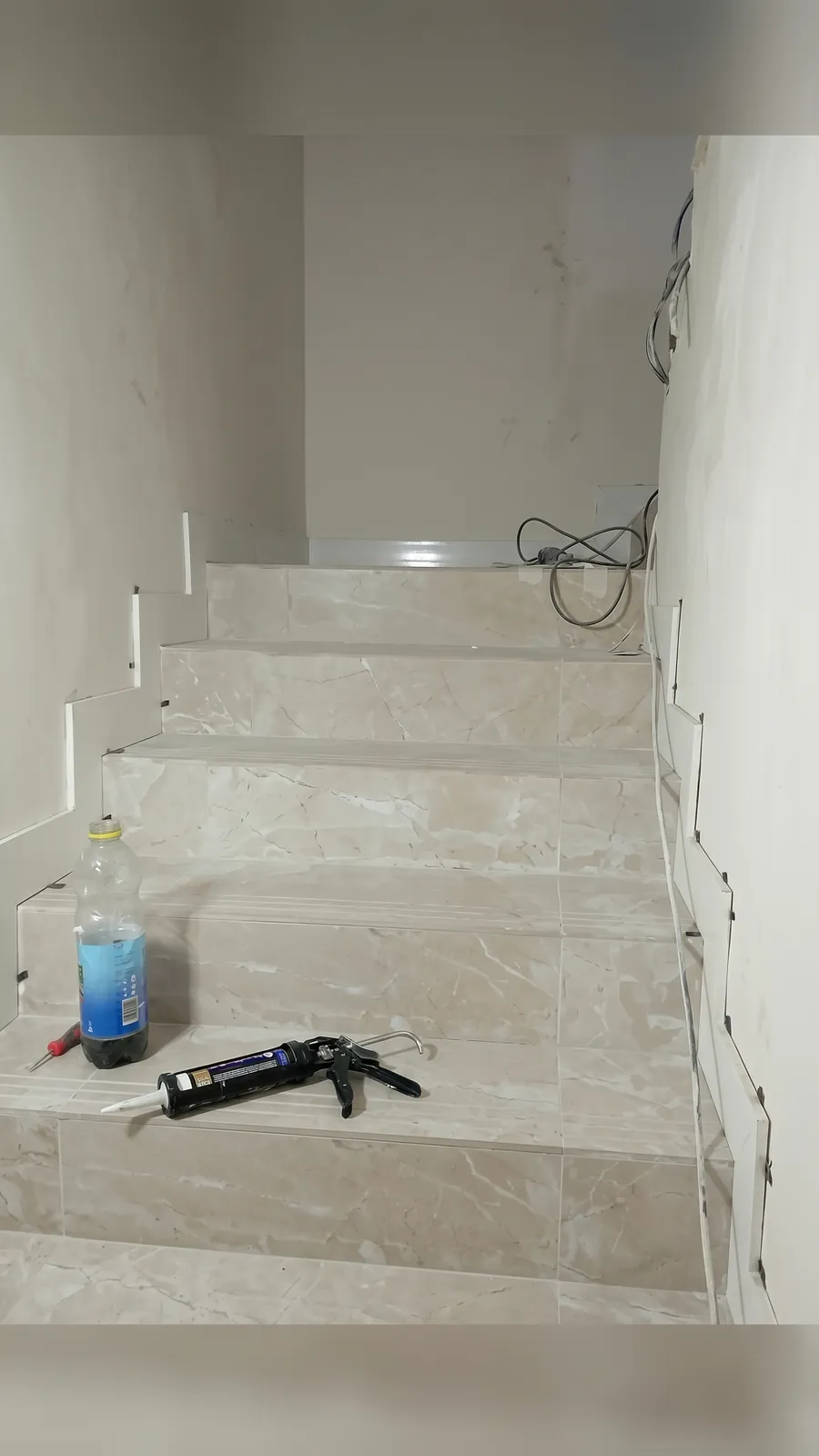 Escalera interior revestida con gres marmolado beige y peldaños con tira antideslizante